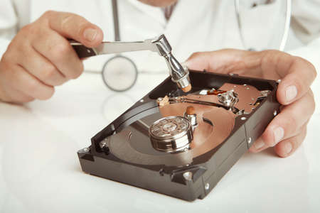 Hard disc drive doctor checking condition of opened 3,5'' drive with hammer
