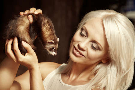 Nice blonde female playing with ferret baby outdoorの写真素材