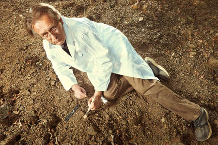 Scientist in terrain looking for trilobite fossil on groundの写真素材