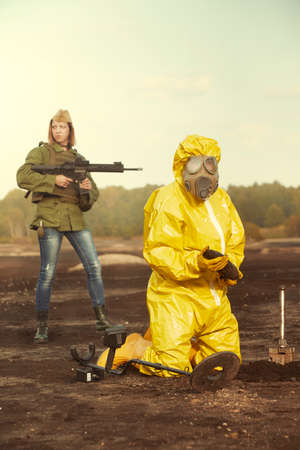 Specialist in chemical protective suit localizing and pick up artillery grenade on fieldの写真素材