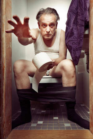 Aging man in a-shirt enjoying his moment on toiletの写真素材