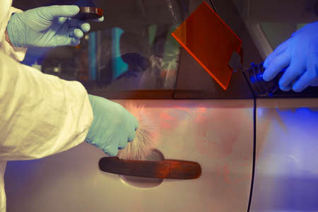 Crime investigation - developing of fingerprints on suspected car in police garage under UV lightの写真素材