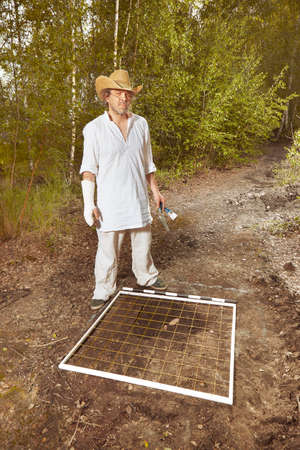 Archeologist on tropical location documenting his excavation work