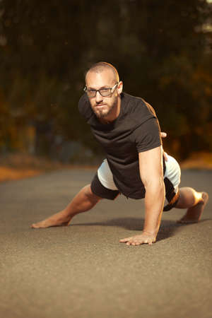 Muscle tattooed man execising on summer city way