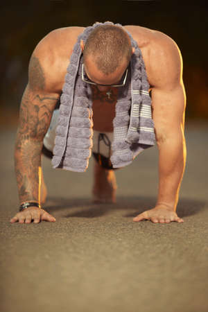 Muscle tattooed man execising on summer city wayの写真素材