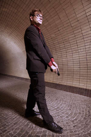 Man in suit on alone city tunnel place with handgunの写真素材