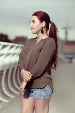 Young redhead woman posing outdoor on bridgeの写真素材