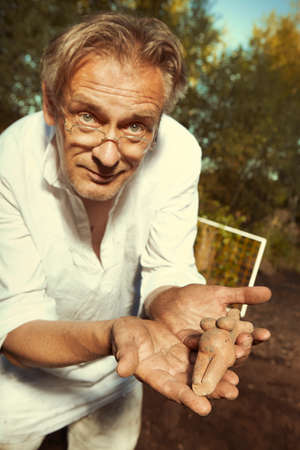 Archaeologist on outdoor location showing his finds