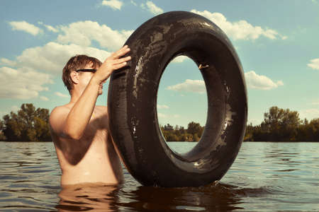 Funny man in sunglasses swimming in lake on inner tubeの写真素材