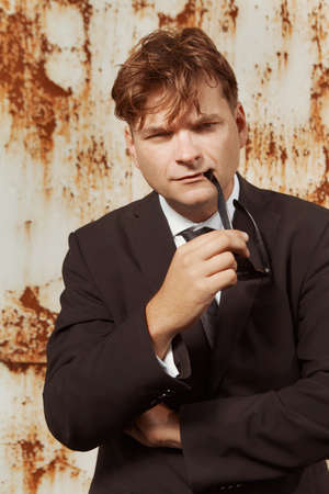 Man in suit and glasses posing by the rusty wallの写真素材