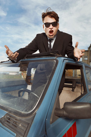 Man in black suit gesturing on his lovely retro carの写真素材
