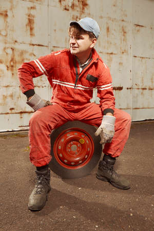Cute man in red overall tunning his lovely retro car