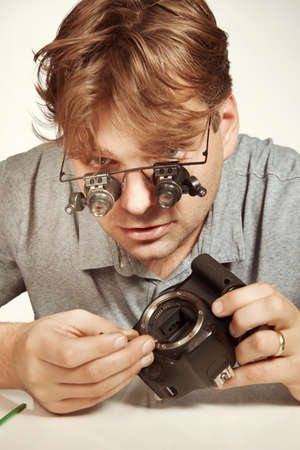 Crazy technician repairing digital camerabody bad way like a doctor
