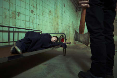 Evil kidnapper holding and controlling young man in horror placeの写真素材