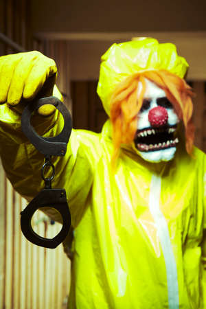 Scary clown man in nightmare style with steel handcuffs