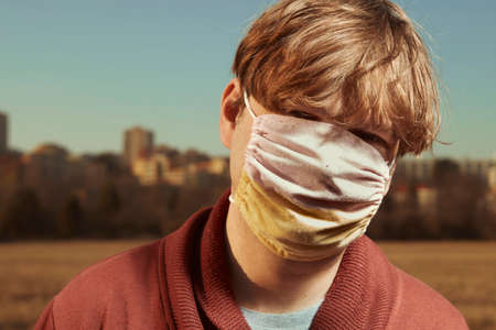 Man in hand made face mask enjoying sunny day on city meadowの写真素材
