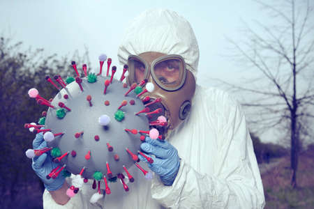 Man in protective antibacterial suit catching virion of coronavirusの写真素材