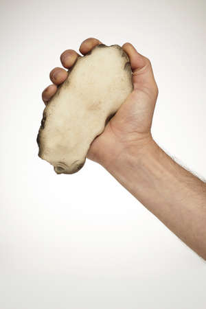 Male hand with stone fist wedge used as a tool or weaponの写真素材