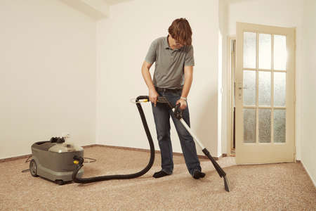 Caucasian man cleaning deeply carpet with wet cleaning machineの写真素材