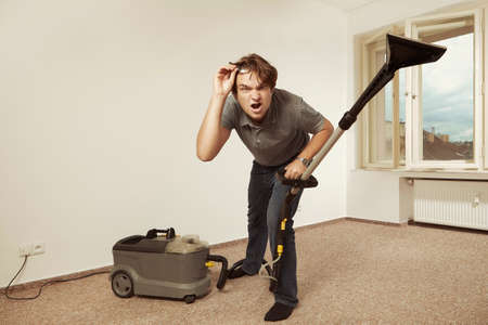 Caucasian man cleaning deeply carpet with wet cleaning machineの写真素材
