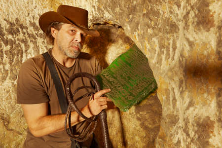 Adventurer in ancient cave on trace of mysterious emerald tablet finding famous artifact