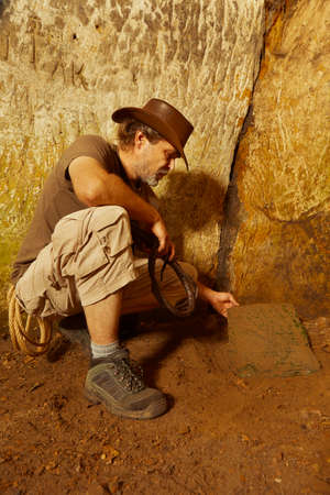 Adventurer in ancient cave on trace of mysterious emerald tablet finding famous artifactの写真素材