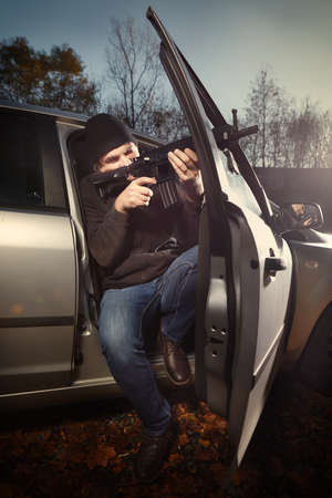 Man with assault carbine waiting for his victim inside car