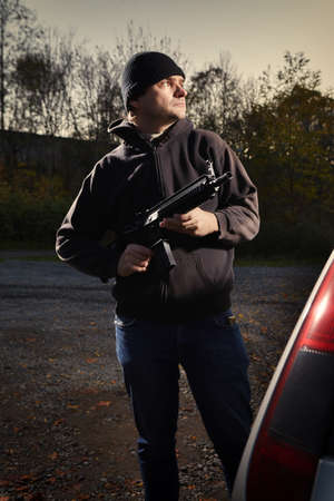 Man with assault carbine waiting for his victim outside his carの写真素材