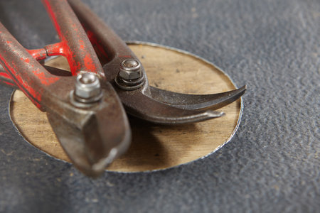 Hand shearing round hole in sheet metal roof components in workroom