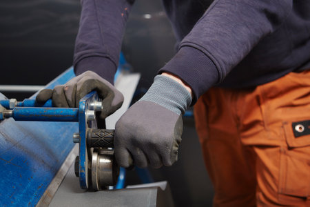Measuring and cutting sheet metal roof components in workroomの写真素材