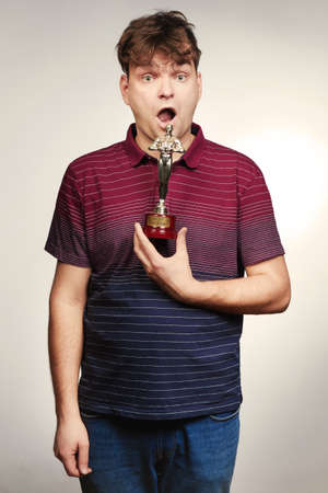 Adult man in striped dress posing with trophyの写真素材