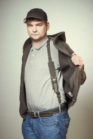 Man in black hooded shirt and black hat showing his dagger