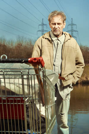 Older beggar man with his property in shopping cartの写真素材