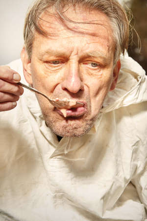 Natural older man in dirty white shirt eating strawberry fruit lunchの写真素材