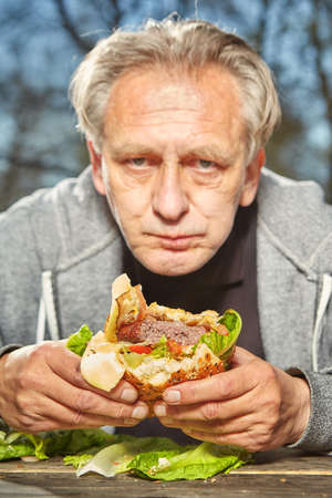 Man in public city park enjoying and eating his hamburger mealの写真素材