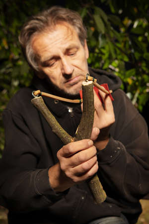 Older man finishing traditional slingshot of wooden forkの写真素材