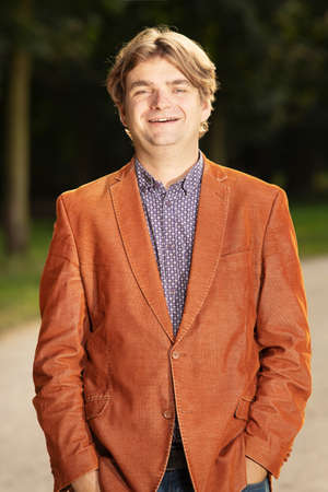 Man in orange jacket posing in early autumn park for portraitの写真素材