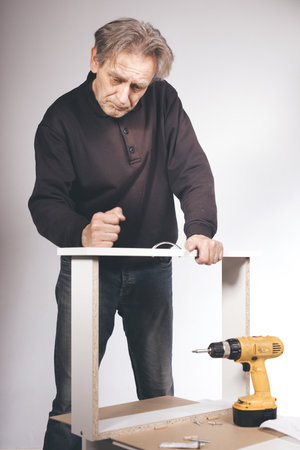 Man assembling set of three laminated wooden drawersの写真素材