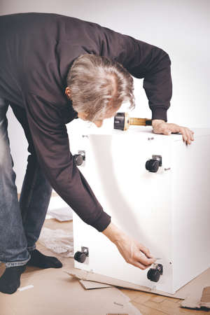 Man assembling set of three laminated wooden drawersの写真素材