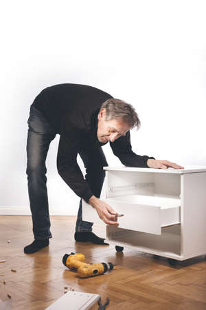 Man assembling set of three laminated wooden drawersの写真素材