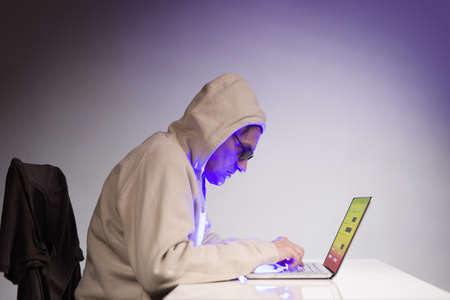 Older criminal man using computer for remote money robberyの写真素材