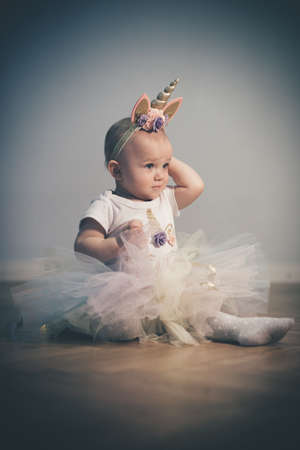 Pretty little girl posing on wooden floor for portraitの写真素材