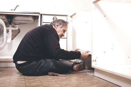 Older man disassembling apartment kitchen out of serviceの写真素材