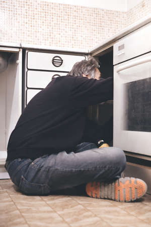 Older man disassembling apartment kitchen out of serviceの写真素材