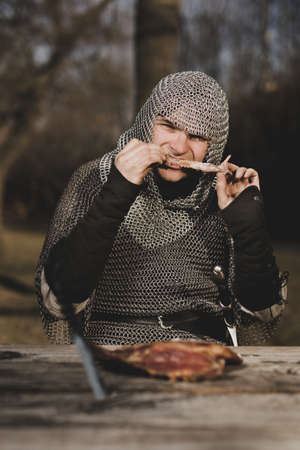 Medieval infantry armed man sitting by the wooden tableの写真素材
