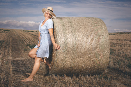 Pretty lady in summer apparel posing on harvested cornfieldの写真素材