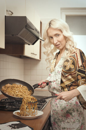 Pretty blonde lady cooking, eating and enjoying her day and off at homeの写真素材