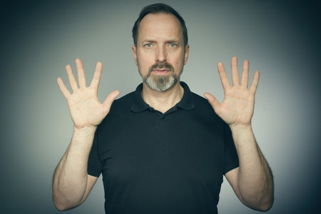 Portrait of aging man trying expressions in studio in black shirtの写真素材