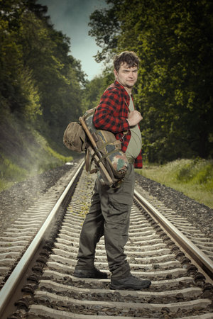 Adventurer with retro haversack wandering nature on railroad wayの写真素材
