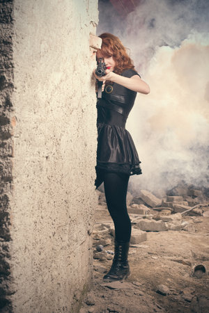Fighter lady observing and looking around in ruins of buildingの写真素材